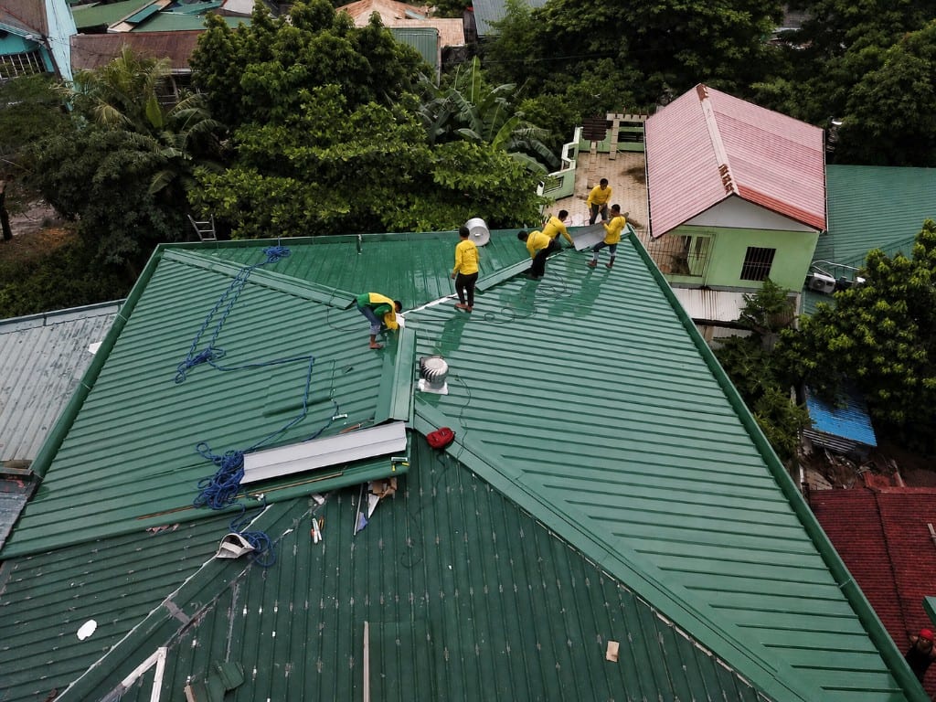 Crew installing a green corrugated metal roof