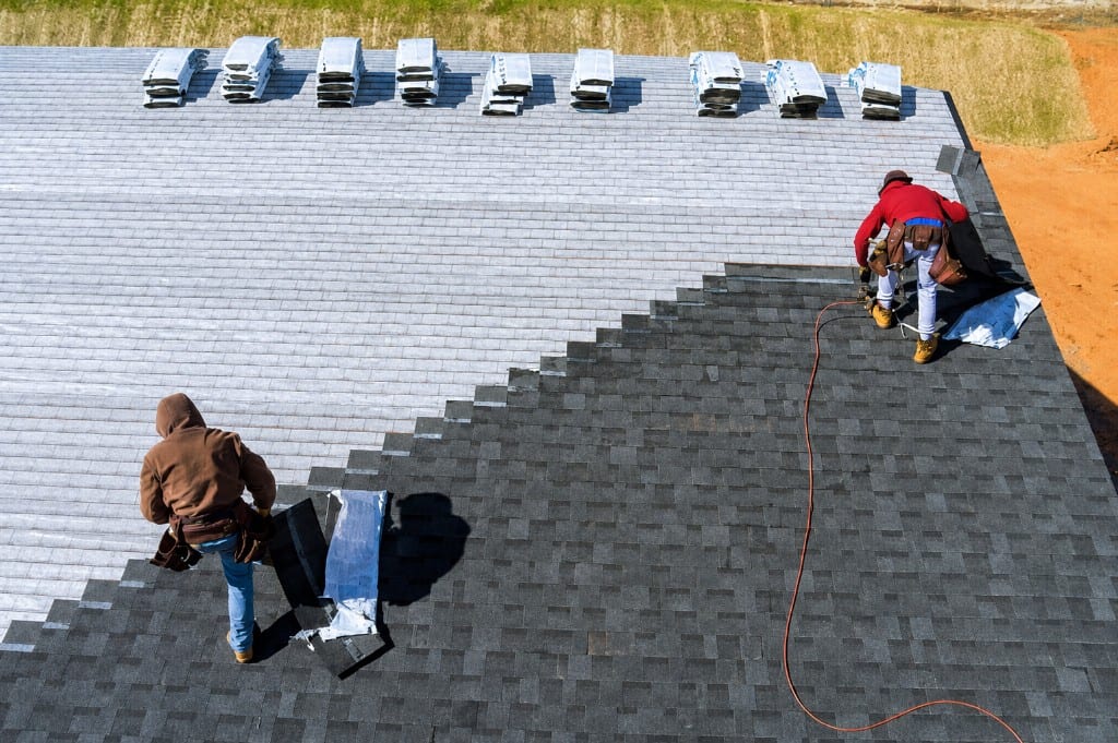 Crew installing charcoal shingles over underlayment