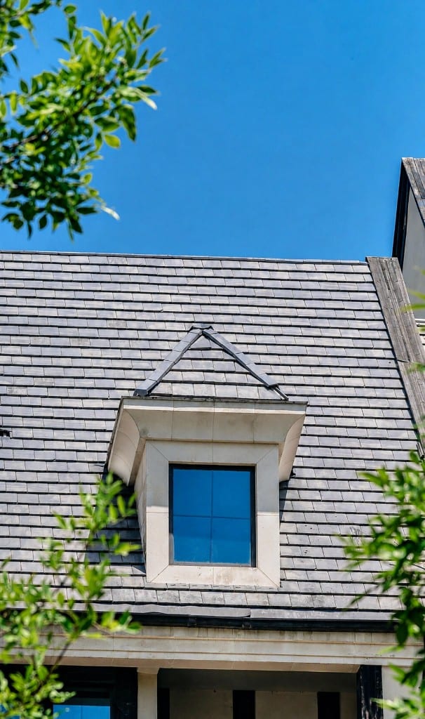 Dark slate-style roof with stone dormer against blue sky