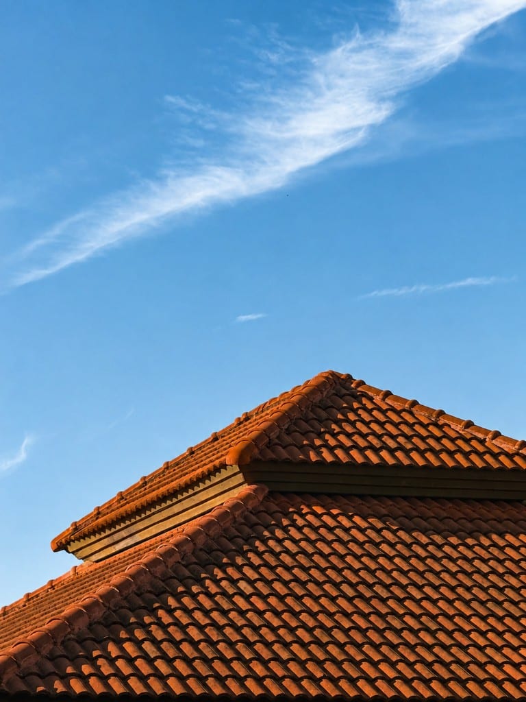 Terracotta clay tile roof peak against blue sky